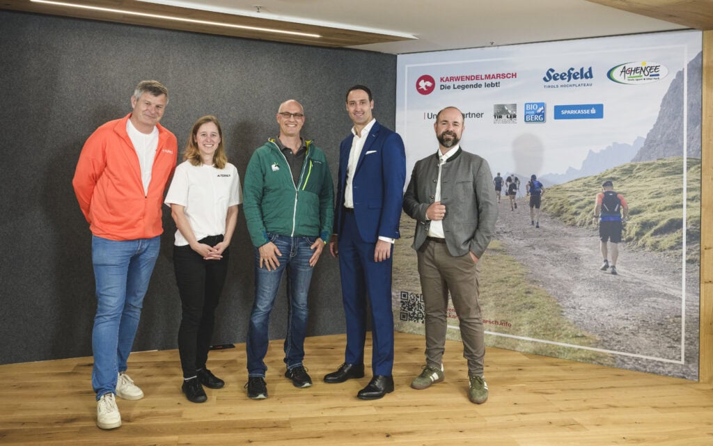 Fünf Personen bei einer Veranstaltung mit Banner.