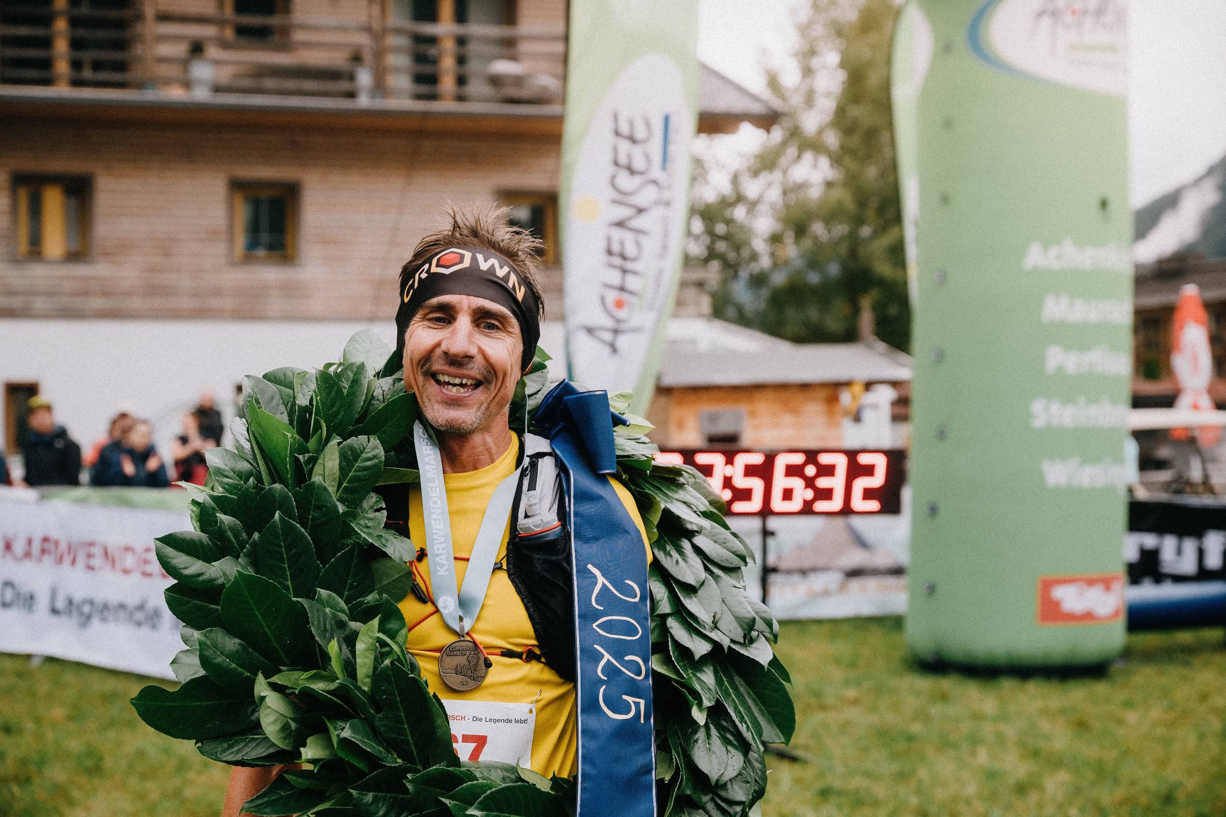Läufer lächelnd mit Siegerkranz und Medaille
