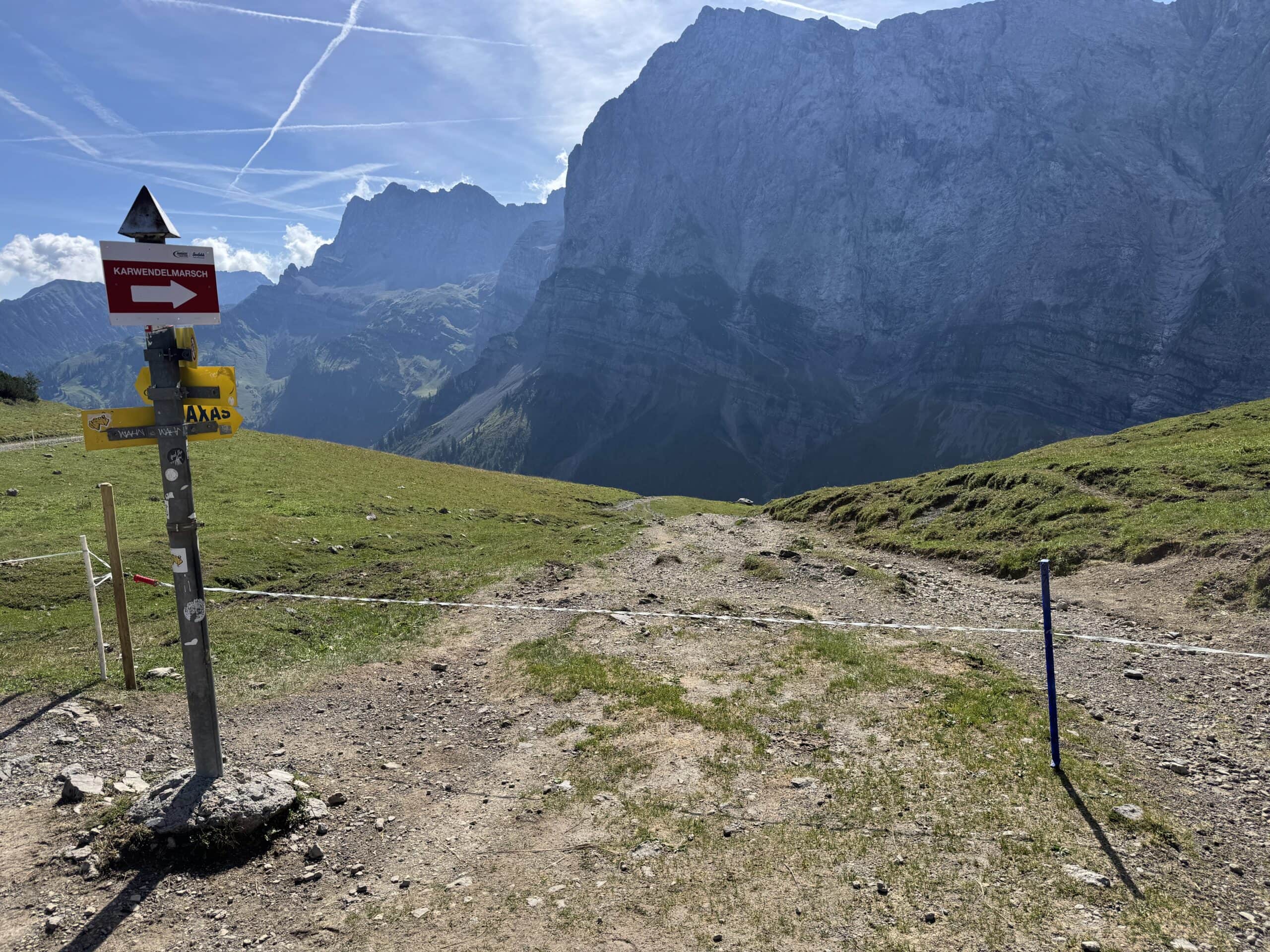 Bergwanderweg mit Wegweisern und Bergpanorama.