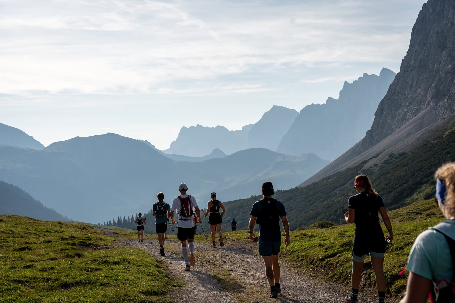 Gruppe wandert auf Bergweg bei Sonnenaufgang.
